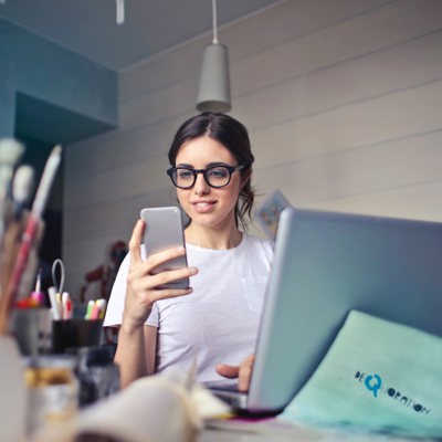 Woman In White T Shirt Holding Smartphone In Front Of Laptop 914931
